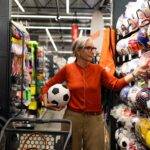 woman shopping sports equipment holding soccer ball sporting goods store day